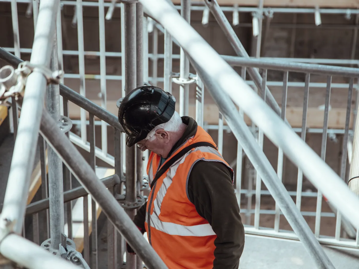 A scaffold worker in high-visibility clothing among metal scaffold poles